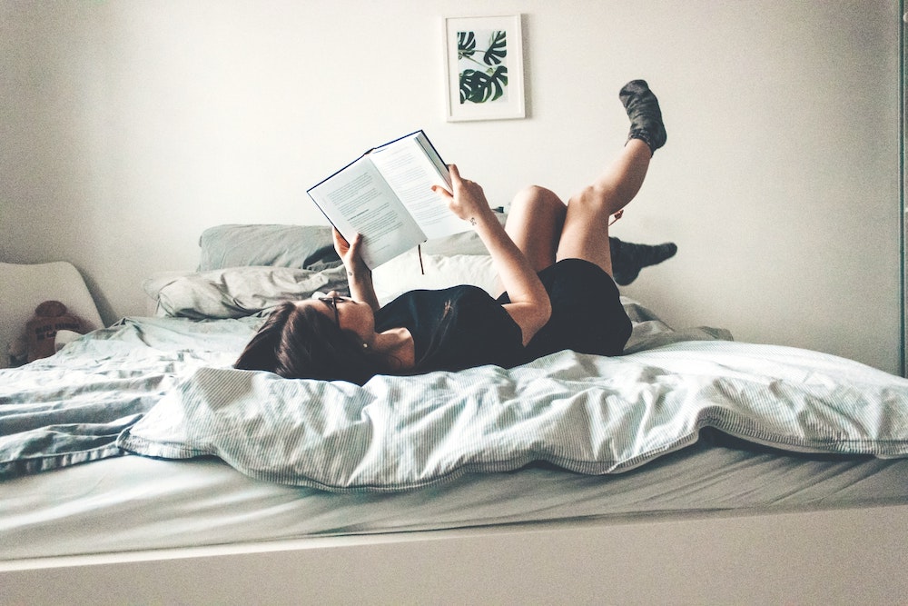 シェアハウスで寝転がりながら本を読む女性